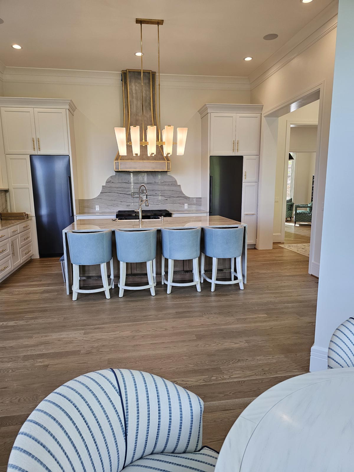 Modern kitchen with large center island, flanking separate fridge and freezer, and feature wall with vent hood and stone slab that matches island