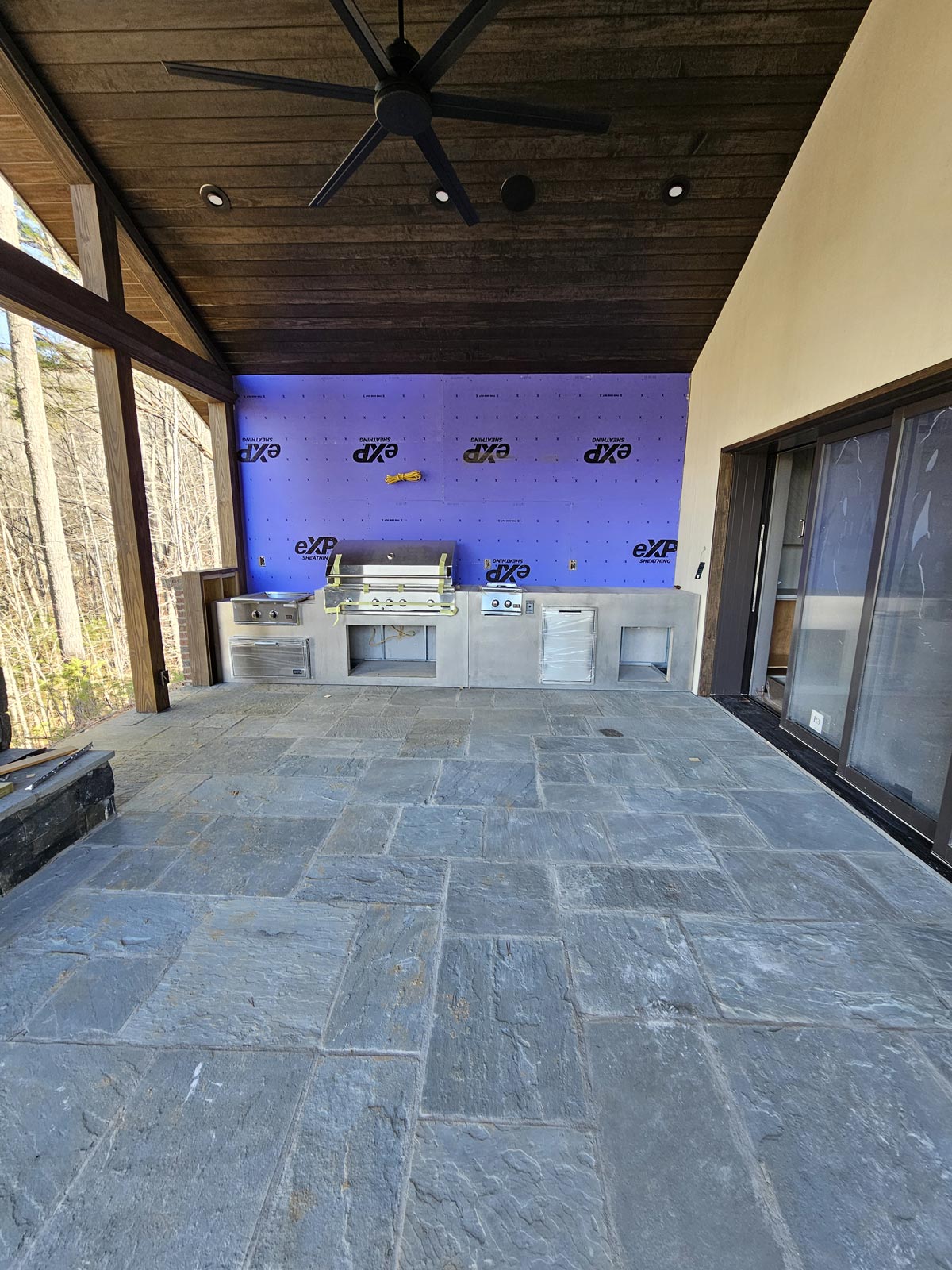 New outdoor kitchen with grilling station under vaulted, wood clad, covered patio 