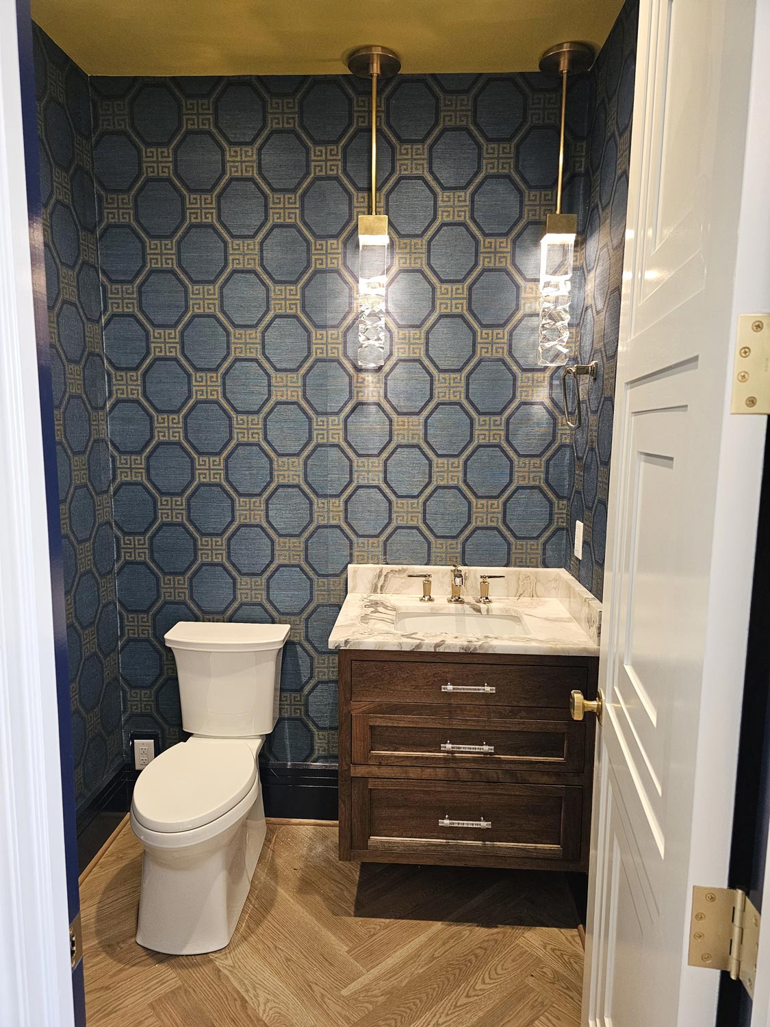 Newly renovated half bath/powder bath renovation in Asheville mountain home with statement wallpaper, herringbone wood flooring, floating vanity