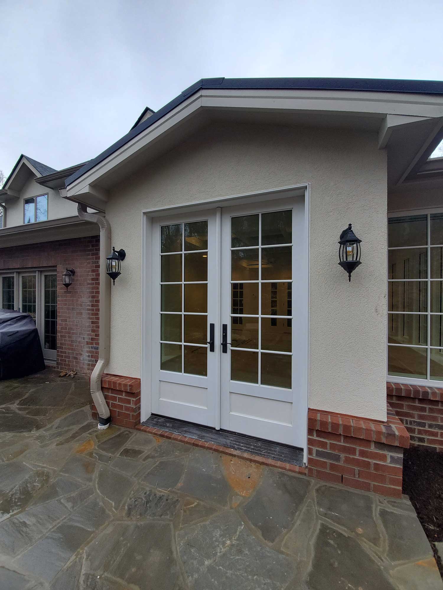 Outside view of french doors with finished patio and buried water draining from gutter Outside view of french doors with finished patio and buried water draining from gutter