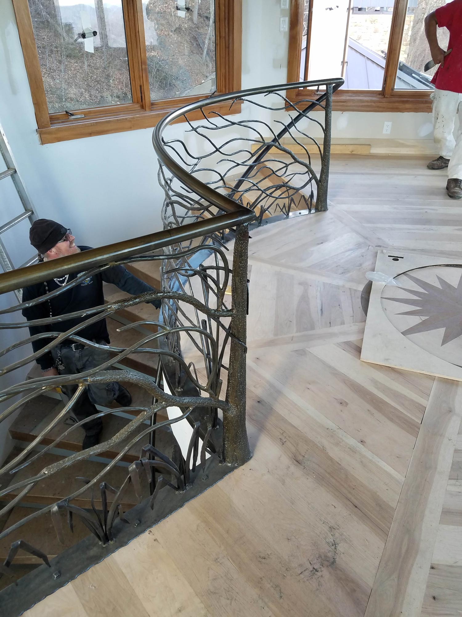 Custom design wood floor pattern compliments the newly installed custom metal stairrail with tree and branch motif Custom design wood floor pattern compliments the newly installed custom metal stairrail with tree and branch motif