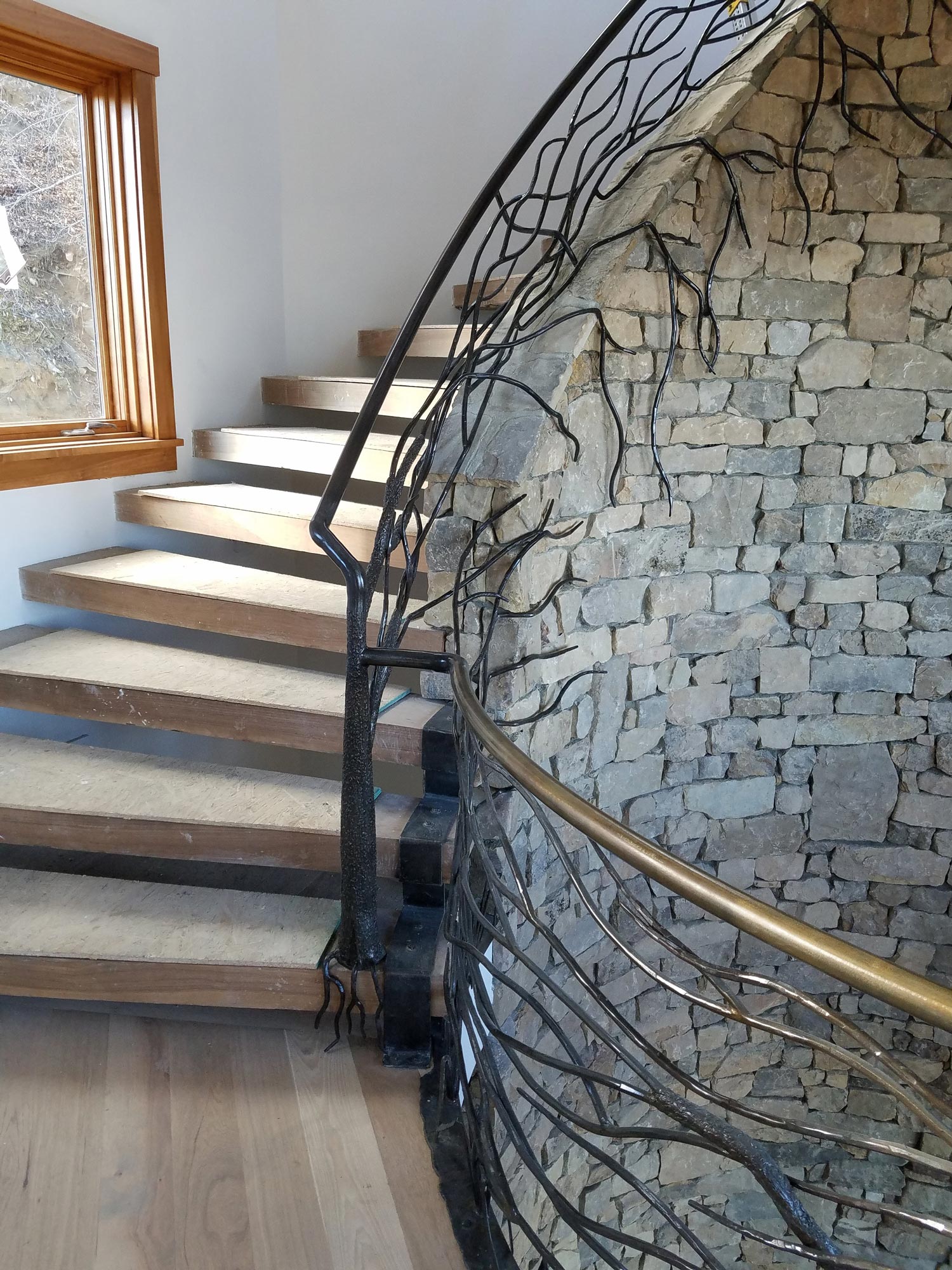Installation of custom iron works on rounded, spiral staircase. With live branches creeping over the stone Installation of custom iron works on rounded, spiral staircase. With live branches creeping over the stone